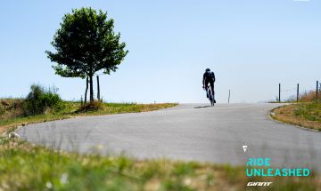 Road cyclist climbs rolling hill